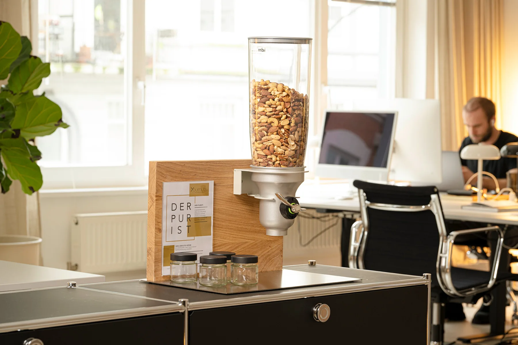 Nussspender mit dem Puristen im Büro, im Hintergrund ein Arbeitsplatz
